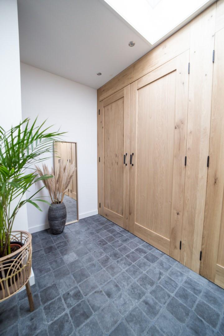 Sfeerfoto van een hal met massieve eiken barndeuren van woodstyles met zwarte deurgrepen. Het eiken geeft een gezellige uitstraling aan het interieur. Bij woodstyles direct uit voorraad leverbaar tegen scherpe prijzen. Snelle bezorging in België en Nederland