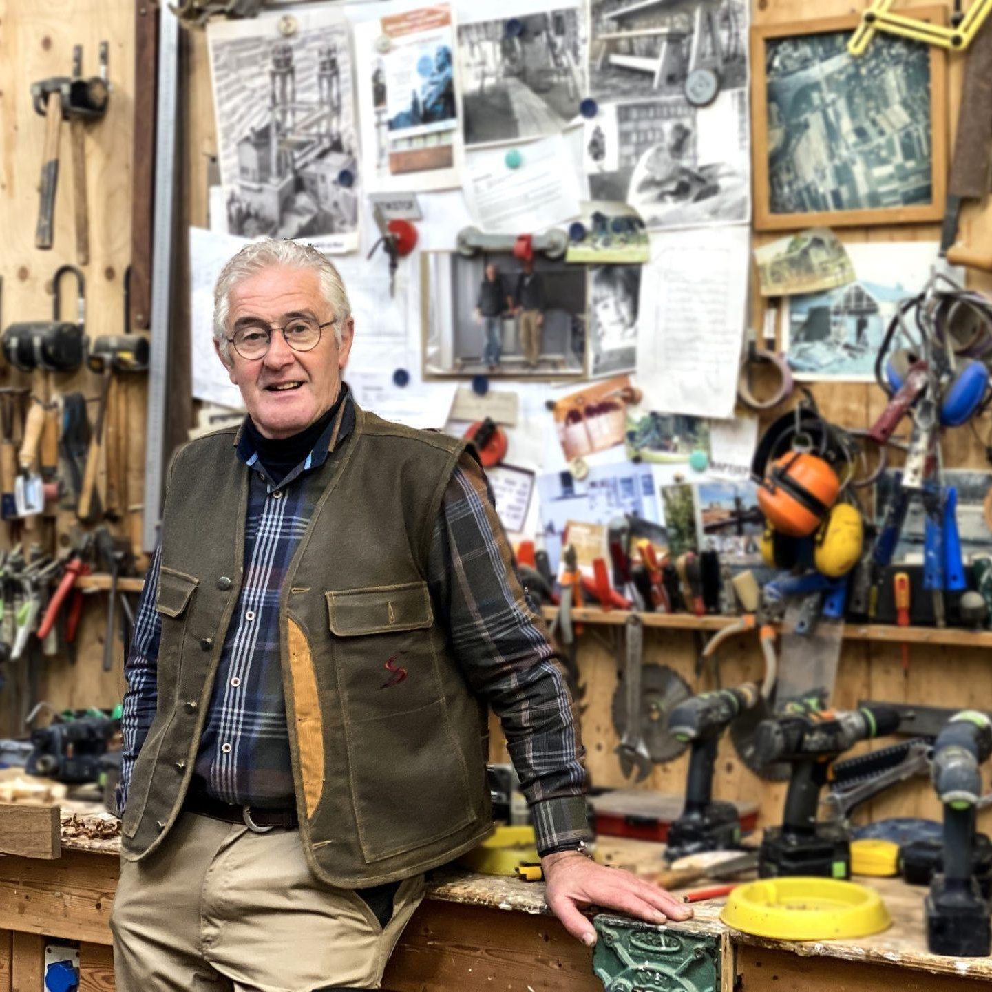 Timmerman in zijn werkplaats met een wand vol gereedschap. Meubelmaker die met eiken panelen werkt.